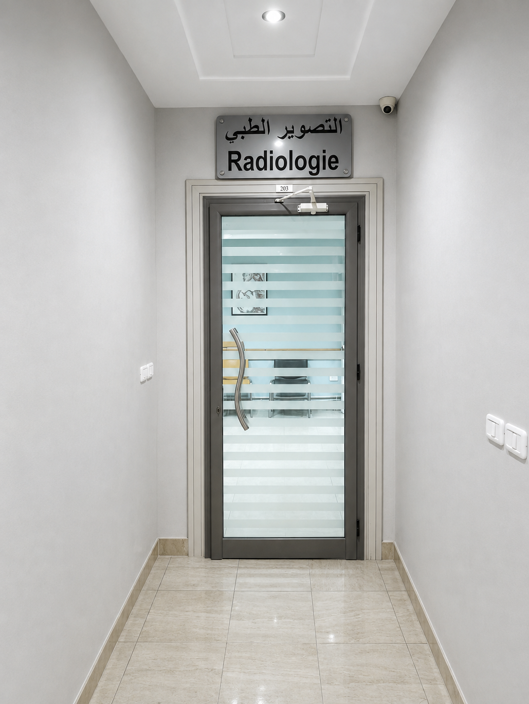 Couloir dégagé menant à la porte vitrée signalée par la plaque « Radiologie »